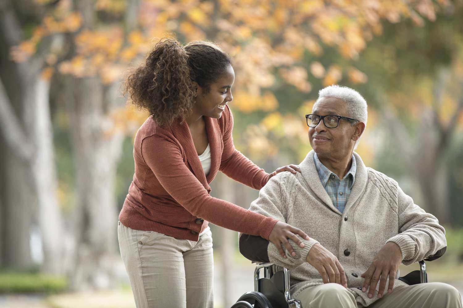 Caregiver assisting an older adult with a walk outside